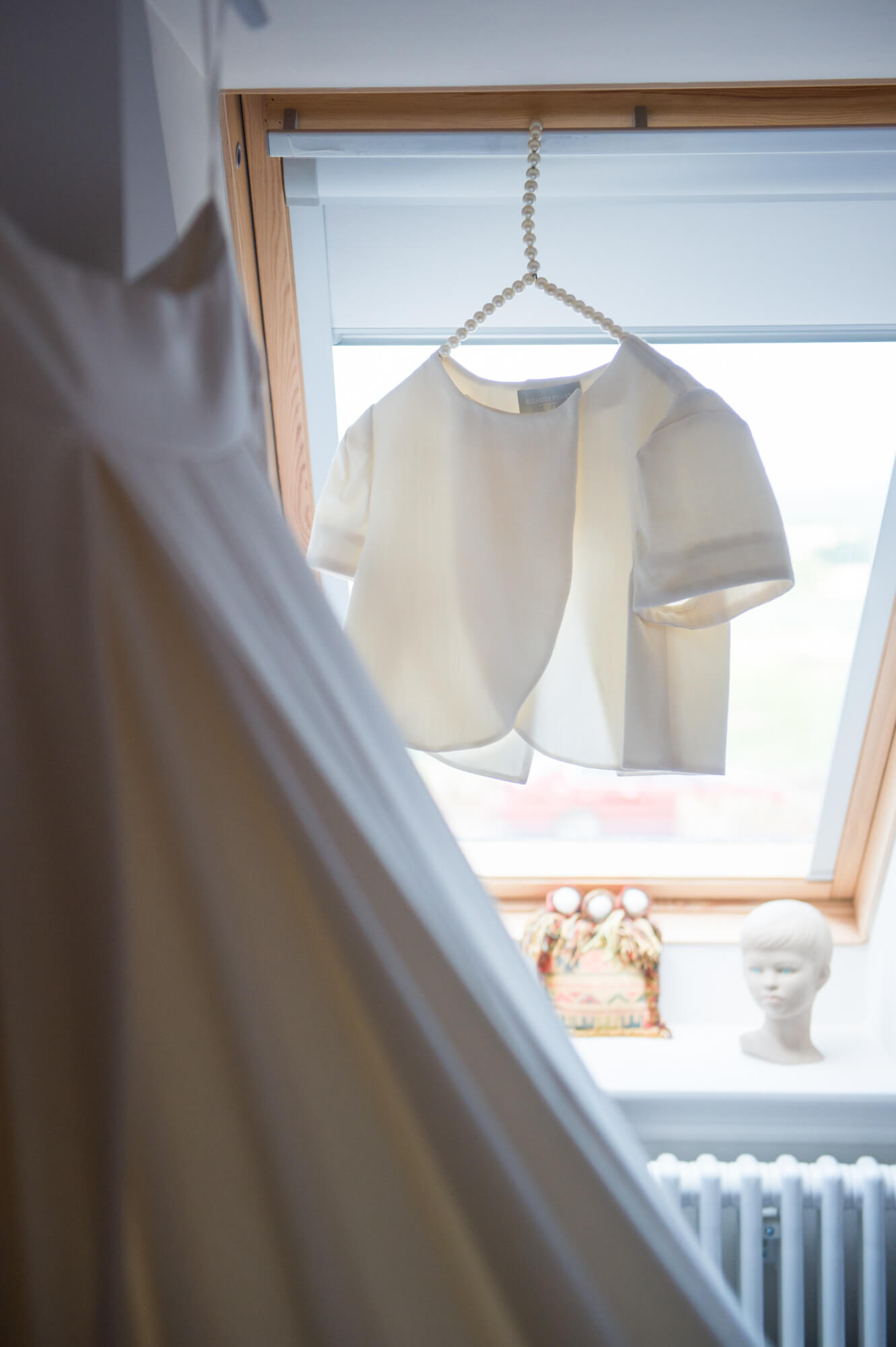 elizabeth stuart wedding gown hanging in front of a window before the wedding by especially amy wedding photography